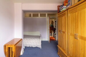 A bedroom with a bed, a wooden wardrobe, and a small table. - Room in shared house in leafy suburban road.  London Zone 4 (Worcester Park)