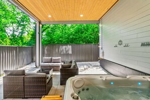 An outdoor patio with wicker furniture, a hot tub, and a wall with the text 'whole inhale.'