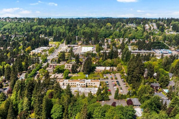 An aerial view of a residential area with houses, a parking lot, and a large building with a flat roof.
