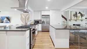 Een moderne keuken met witte kasten, een roestvrijstalen fornuis en een ingebouwde magnetron.