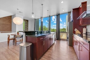 Une cuisine moderne dotée d’un grand îlot central, de meubles en bois et offrant une vue sur l’extérieur.