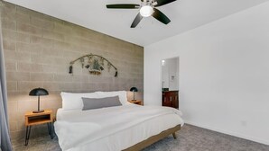 A bedroom with a bed, two bedside tables, a ceiling fan, a brick wall, and a mirror. - Exquisite apartment with 2 balconies - Pool!! (Tempe)