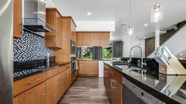 Une cuisine moderne avec des meubles en bois, un crédence carrelée en noir et blanc et un lave-vaisselle.