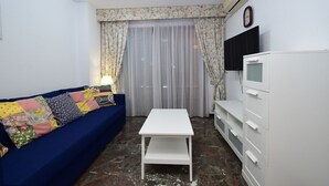 A living room with a blue sofa, a white table, and a white cabinet. - BENIBEACH (1 BEDROOM) (Benidorm)