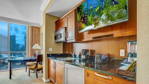 A modern kitchen with wooden cabinets, stainless steel appliances, and a large aquarium above the counter. - Strip View MGM Signature  Studio ★ No resort fees (Las Vegas)
