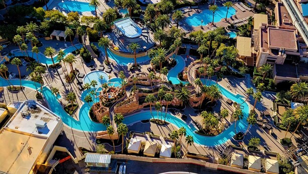 An aerial view of a resort with multiple swimming pools, palm trees, and a variety of architectural structures. - Strip View MGM Signature  Studio ★ No resort fees (Las Vegas)