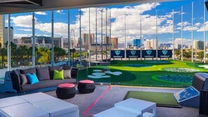 A modern lounge area with a city view, a green artificial golf course, and a sofa with colorful cushions. - Strip View MGM Signature  Studio ★ No resort fees (Las Vegas)
