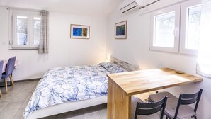 Un dormitorio con una cama, un escritorio de madera, dos sillas y dos cuadros en la pared.