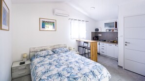 Un dormitorio con cama, mesita de noche y una pequeña zona de escritorio con silla.