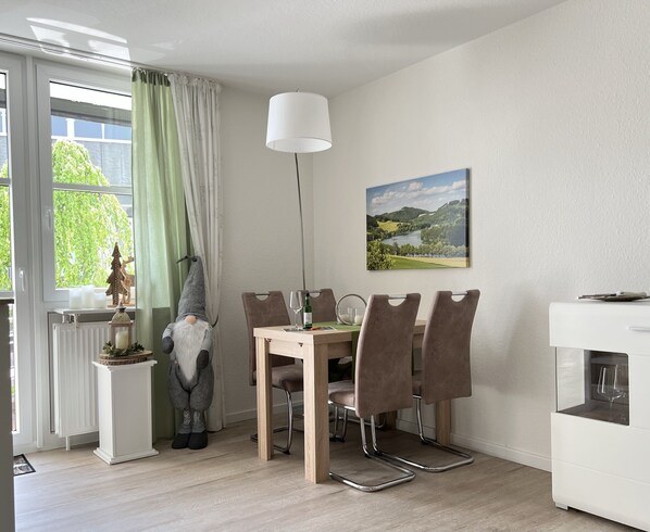 A dining area with a table, chairs, a lamp, and a painting on the wall.