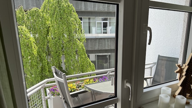 A balcony with a view of a green tree and a building in the background. - Waldläufer Brilon (Brilon)