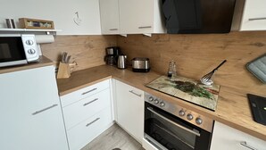 A modern kitchen with white cabinets, a microwave, a coffee maker, a toaster, and a wooden countertop. - Waldläufer Brilon (Brilon)