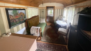 A cozy room with a bed, a green sofa, a small table, and a TV. - Zirkuswagen am Landhaus Labes (Stechlin)