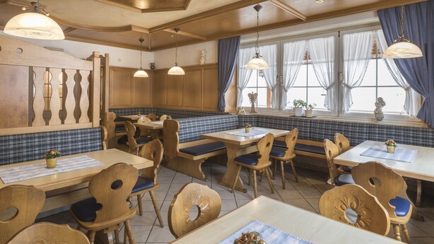 A restaurant with wooden furniture, blue and white checkered booths, and pendant lighting. - Landgasthof Krone (Offingen)