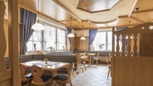 A restaurant with wooden furniture, a checkered floor, and large windows with curtains. - Landgasthof Krone (Offingen)
