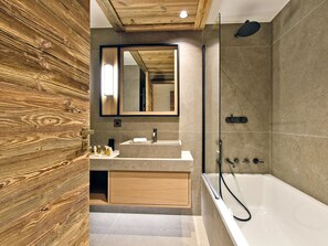 A modern bathroom with a wooden wall, a large mirror, a sink, and a bathtub. - Ski-in ski-out apartment with concierge in Méribel (Méribel)