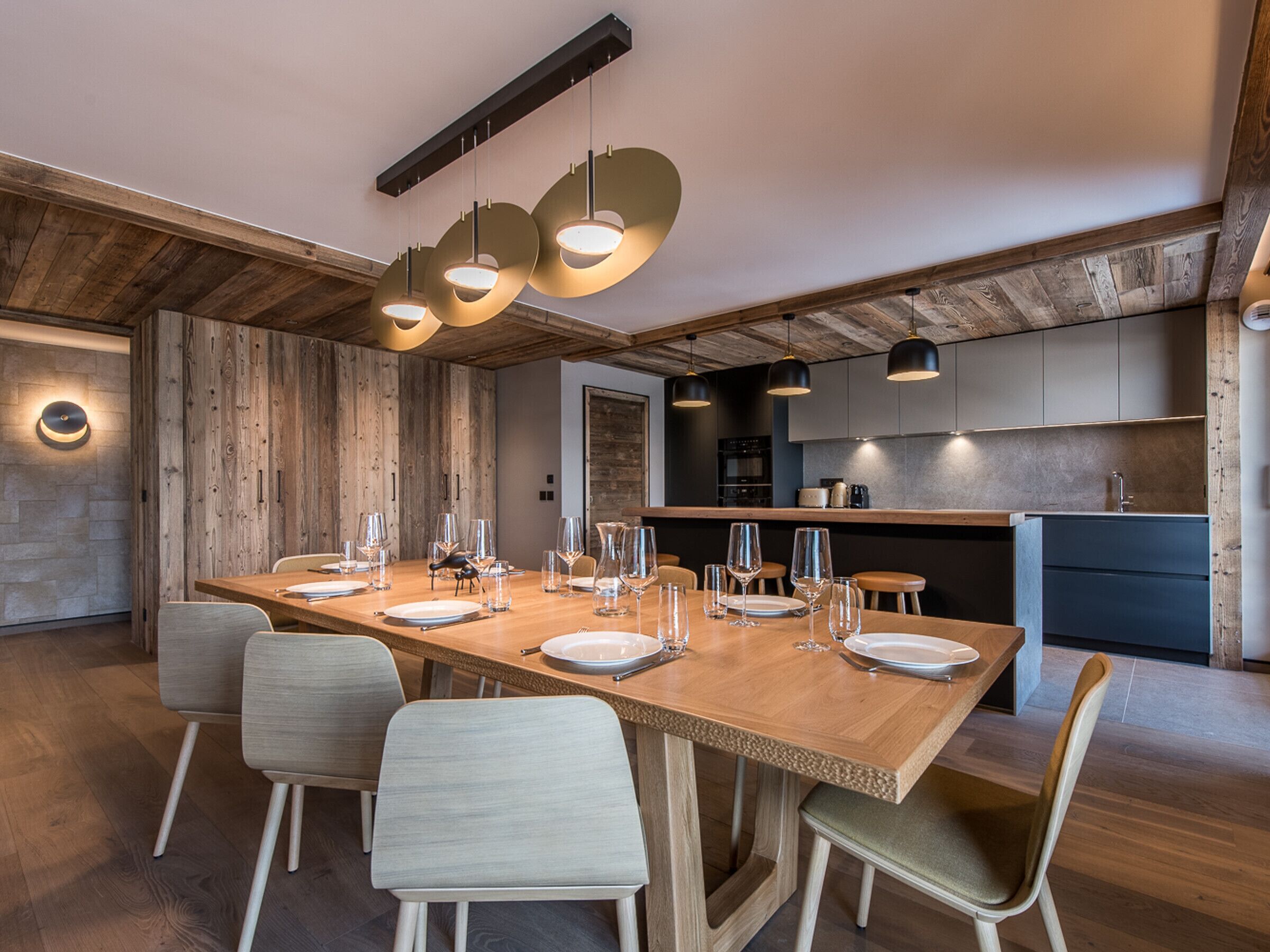 Un espace repas moderne avec une longue table en bois, dressée pour six personnes, entourée de chaises.