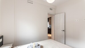A bedroom with a neatly made bed, a bedside table, and a door leading to a bathroom. - El Rincón del Baluarte by H - Centro Ayamonte AVHVIIISP (Ayamonte)