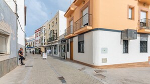 A street with buildings, including a white building with a balcony and a sign that reads "ESTETICA Arima." - El Rincón del Baluarte by H - Centro Ayamonte AVHVIIISP (Ayamonte)