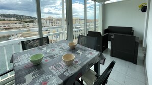 A balcony with a table set for two, overlooking a cityscape. - 2-room mezzanine, private parking, pets allowed (Sète)