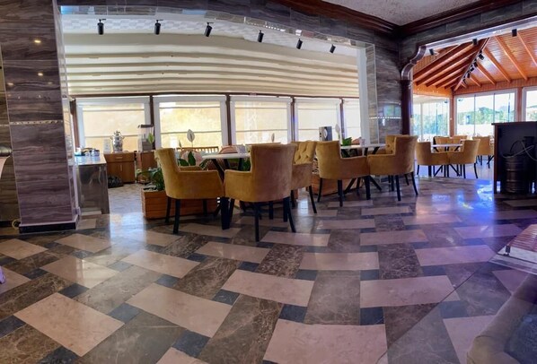A spacious lobby with a checkered floor, yellow chairs, and a large wooden ceiling structure.
