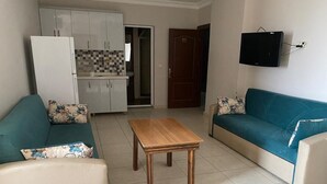 Ein Wohnzimmer mit einer Couch, einem Couchtisch und einem an der Wand befestigten Fernseher.