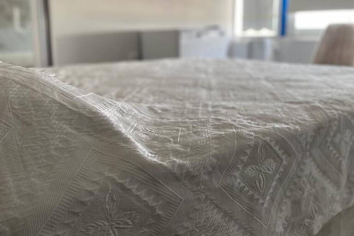 Ein Bett mit einer bettbezogenen Tagesdecke mit Struktur und Muster.