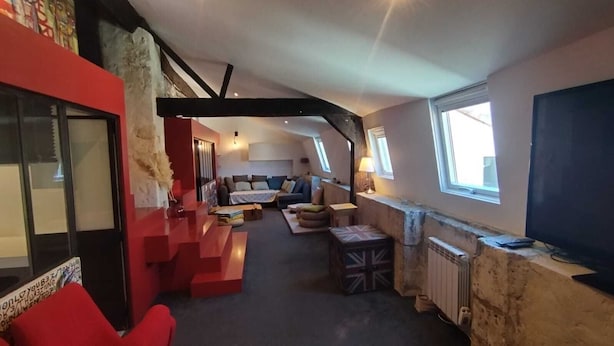 A loft-style living room with a high ceiling, exposed beams, and a mix of modern and rustic decor. - Bel Appartement Atypique au Coeur de La Rochelle (La Rochelle)