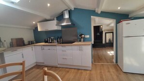 A modern kitchen with white cabinets, a stainless steel range hood, and a built-in oven. - Bel Appartement Atypique au Coeur de La Rochelle (La Rochelle)