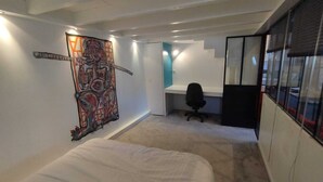 A bedroom with a bed, a desk, and a chair. There is a colorful artwork on the wall. - Bel Appartement Atypique au Coeur de La Rochelle (La Rochelle)