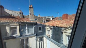 A view of a residential area with terracotta-tiled roofs, a mix of building styles, and a clear blue sky. - Bel Appartement Atypique au Coeur de La Rochelle (La Rochelle)