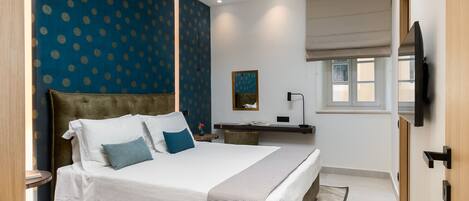 A modern bedroom with a large bed, a ceiling fan, a bedside table, a nightstand, a mirror, and a window with a view.