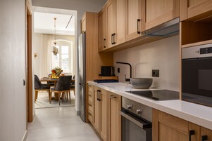 A modern kitchen with wooden cabinets, a stainless steel refrigerator, a microwave, and a stove.