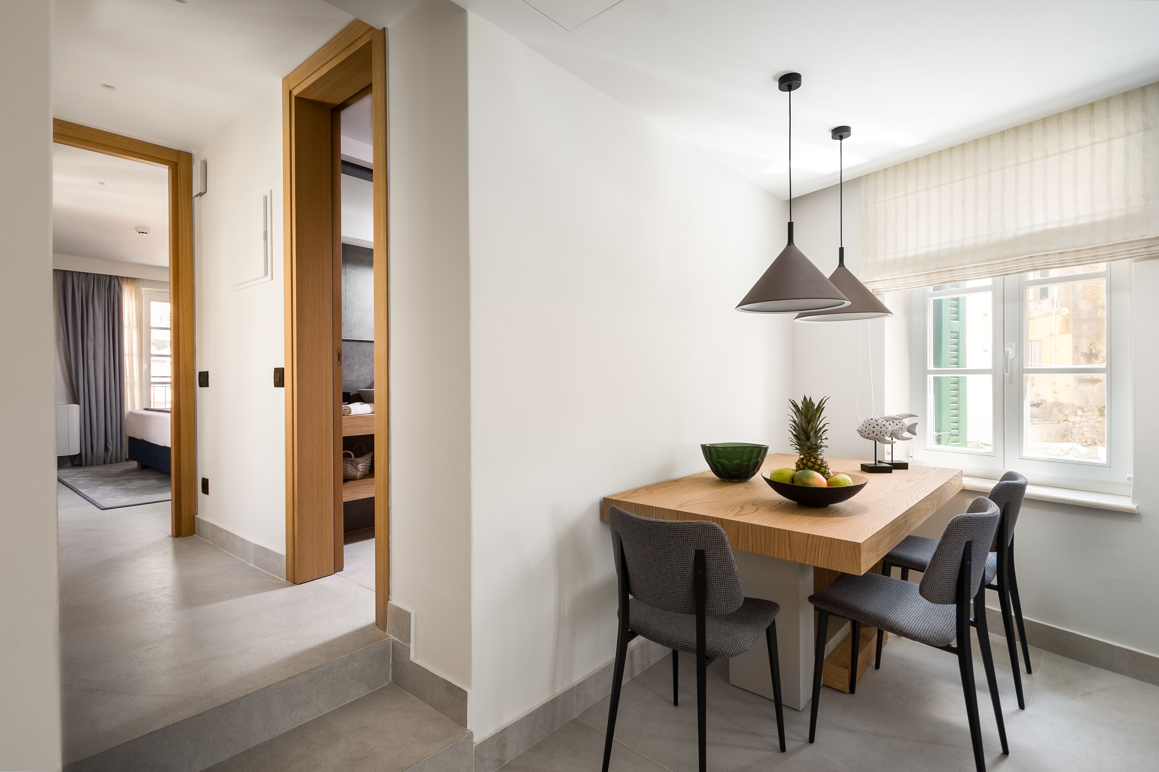 Un espace repas moderne avec une table en bois, quatre chaises et un luminaire suspendu.