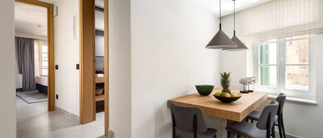 A modern dining area with a wooden table, four chairs, and a pendant light.