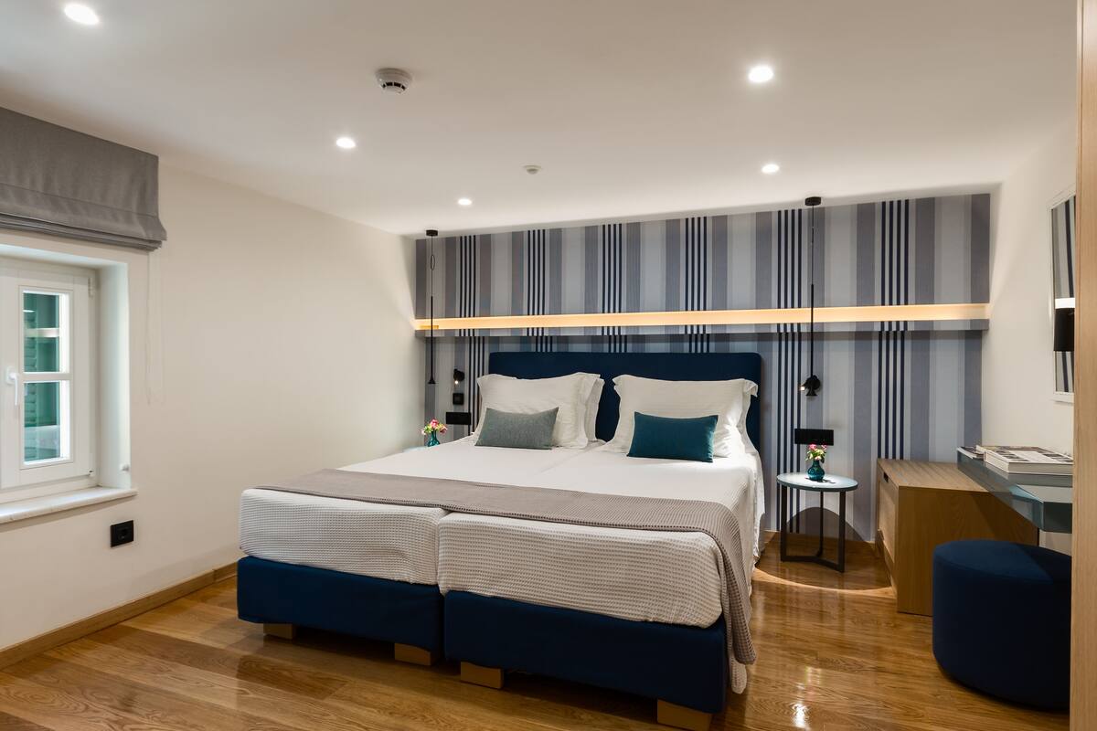 A modern bedroom with a large bed, bedside tables, a desk, and a window.