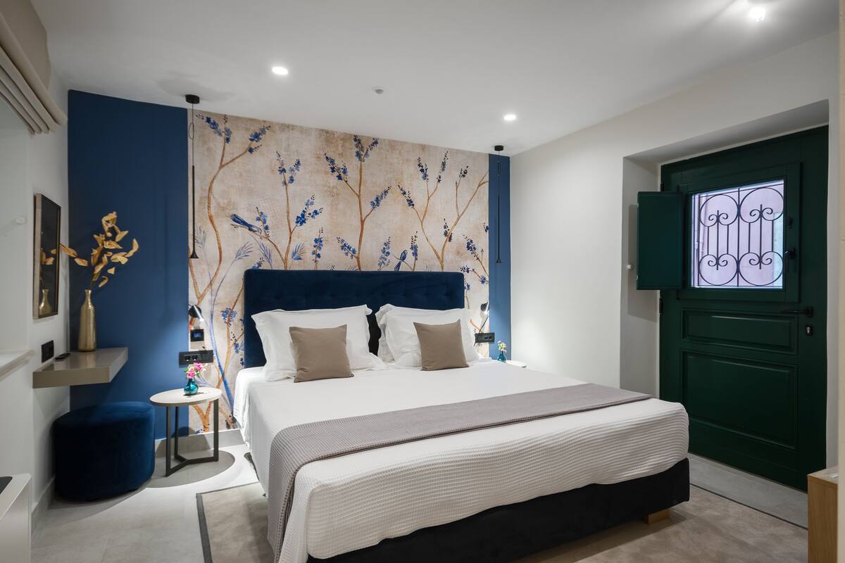 A modern bedroom with a large bed, a blue accent wall, and a green door.
