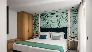 Een moderne slaapkamer met een groot bed, een houten garderobe, een nachtkastje en een muur met een bladerenmotief.