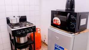 Et lille køkken med gasblus, mikroovn og køleskab.