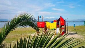 A playground with colorful play structures near a body of water. - T2 Apartment with large terrace, parking, pets allowed, and pool (Le Barcarès)