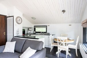 Un espacio habitable compacto con kitchenette, comedor y sofá.