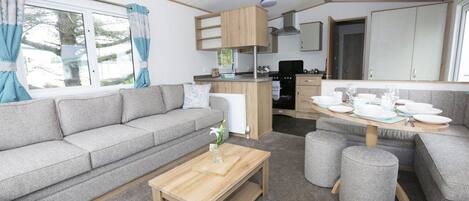 A compact living space with a sofa, a wooden coffee table, and a dining area with stools.