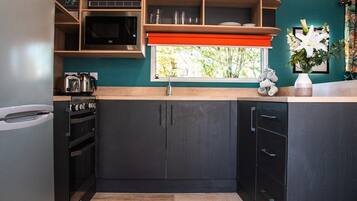 A modern kitchen with dark cabinetry, a microwave, and a sink.