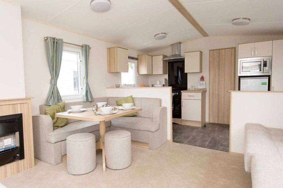 Un espacio habitable compacto con kitchenette, una zona de comedor con mesa y sillas, y un sofá.