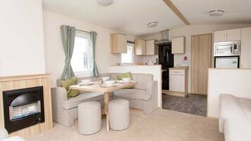 A compact living space with a kitchenette, a dining area with a table and chairs, and a sofa.