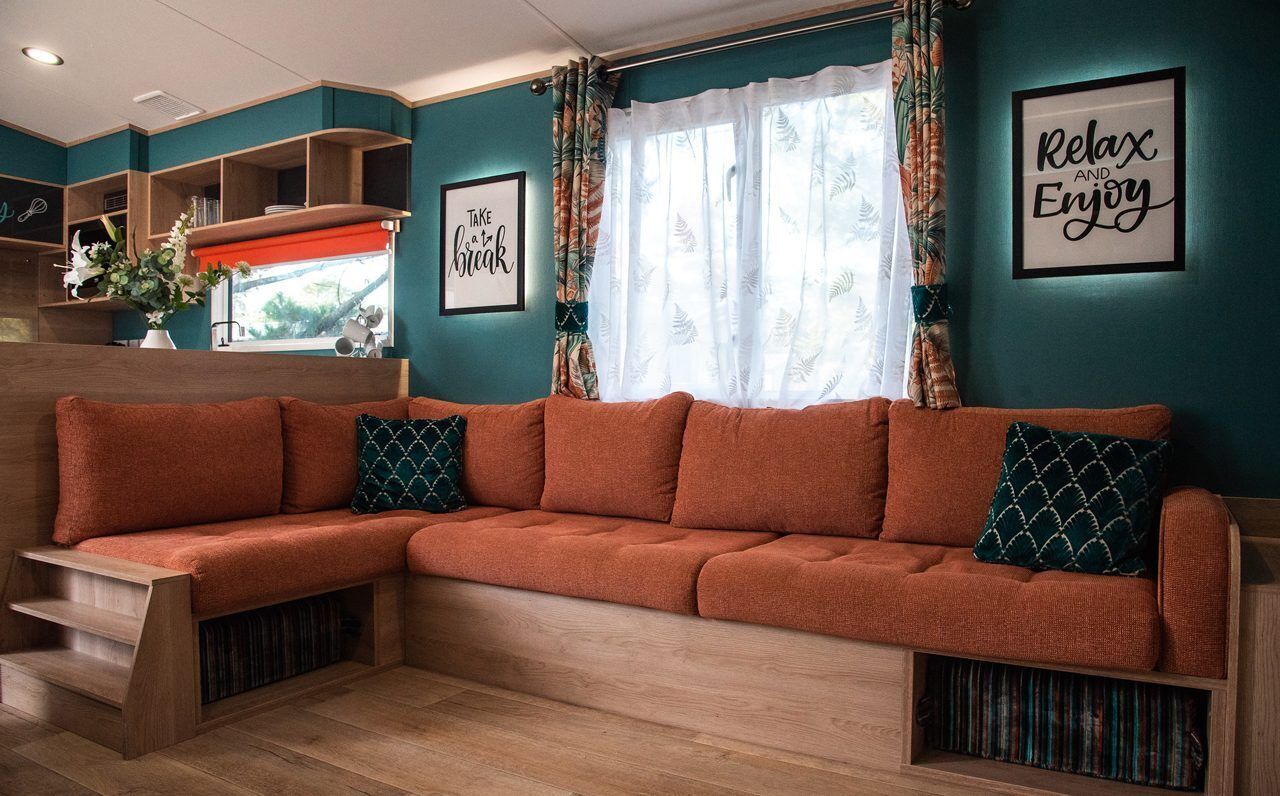 A cozy living room with a sectional sofa, wooden shelves, and a window with curtains.