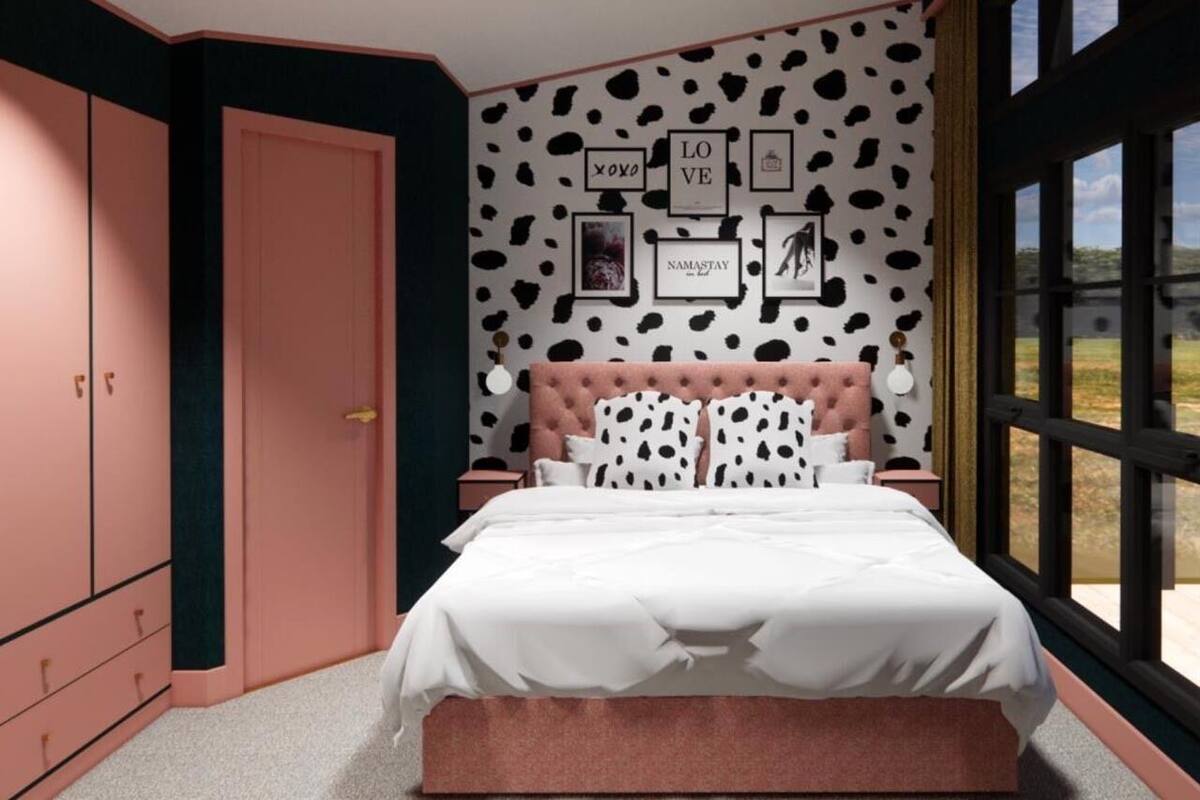 Un dormitorio con cama, armario, una pared adornada con marcos y una ventana con vistas.