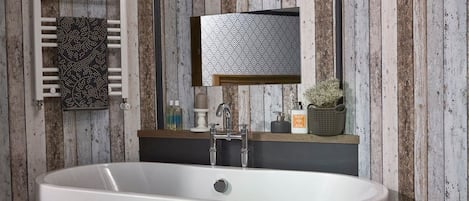 Une salle de bain moderne avec une baignoire sur pieds, un grand miroir et un mur en bois.