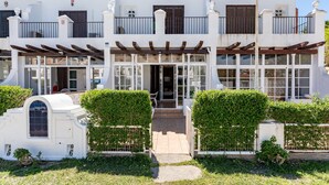 A two-story building with a white facade, balconies, and a covered entrance. - Holiday Home 'Townhouse beachside Fuengirola' with Shared Pool & Wi-Fi (Fuengirola)