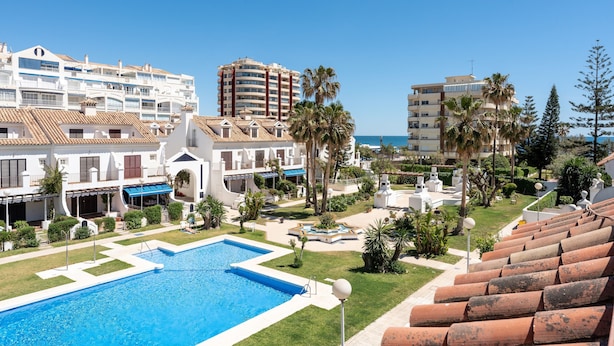 A resort with a swimming pool, palm trees, and a view of the sea. - Holiday Home 'Townhouse beachside Fuengirola' with Shared Pool & Wi-Fi (Fuengirola)
